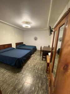 1 dormitorio con 2 camas, mesa y puerta en HOTEL FLAMINGOS DE CIUDAD GUZMAN, en Ciudad Guzmán