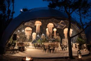 Big Bang Nature Stays في صوص دي بورتيزولو: خيمة فيها طاولات وكراسي في الليل