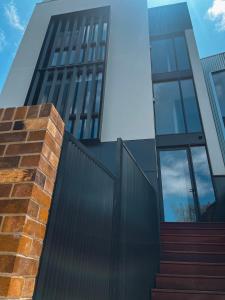 un edificio con una valla y escaleras delante en The Green Rooms - Luxury themed micro apartments inspired by tiny home design, en Canberra