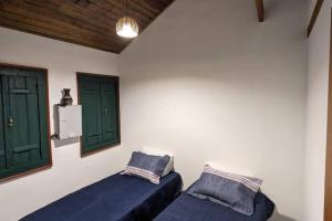 a room with two beds and two green windows at Casa histórica do escravo isidoro in Diamantina
