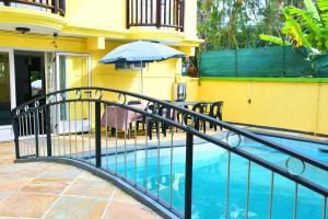 a fence next to a swimming pool with an umbrella at Eden Holidays Resort- Poste Lafayette in Poste Lafayette