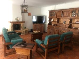een woonkamer met een bank en stoelen en een tv bij Paradise Valley House in São Martinho do Porto