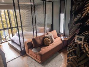 sala de estar con sofá marrón frente a una ventana en The Green Rooms - Luxury themed micro apartments inspired by tiny home design, en Canberra