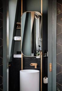 W łazience znajduje się biała umywalka i lustro. w obiekcie The Green Rooms - Luxury themed micro apartments inspired by tiny home design w mieście Canberra