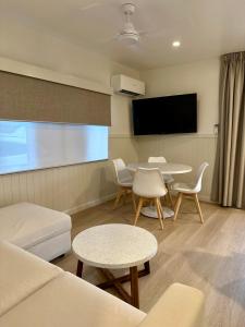 uma sala de estar com um sofá e mesas e uma televisão de ecrã plano em Lake Tinaroo Holiday Park em Tinaroo