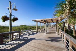 a wooden boardwalk leading to the beach with benches at Three Sea in Carolina Beach