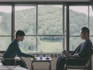 two people sitting in chairs in front of a window at Chalet Shiga in Yamanouchi