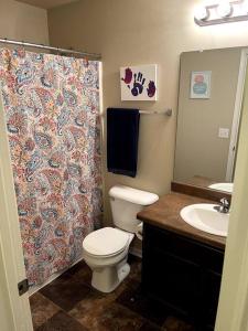 a bathroom with a toilet and a shower curtain at Cheerful 3 bd home with easy access to interstate! in Omaha