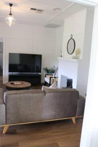 ein Wohnzimmer mit einem Sofa und einem TV in der Unterkunft Gladbyrne in Braidwood