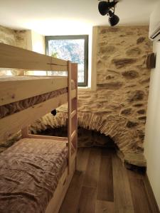 a room with two bunk beds and a stone wall at U MULINU in Moïta