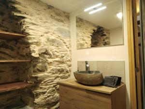 a bathroom with a sink and a stone wall at U MULINU in Moïta