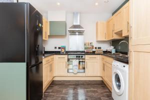 a kitchen with wooden cabinets and a black refrigerator at Hidden Gem 2BR flat wBalcony near Surrey Quays in London