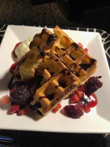 a white plate with waffles and berries on a table at HOTEL Sweets in Mobara