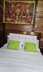 Una cama con dos almohadas verdes encima. en Le Chalet Kapélet en Kribi