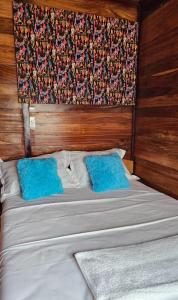 a bed with two blue pillows on top of it at Le Chalet Kapélet in Kribi