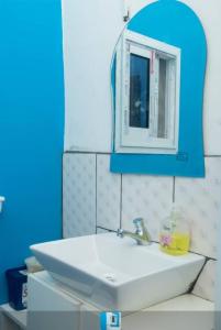 a bathroom with a white sink and a blue mirror at Le Chalet Kapélet in Kribi