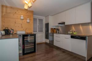a kitchen with white cabinets and a wooden wall at Am Strubelweg in Adelboden