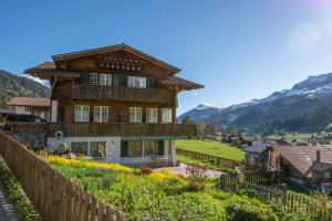 a large wooden house with mountains in the background at Am Strubelweg in Adelboden