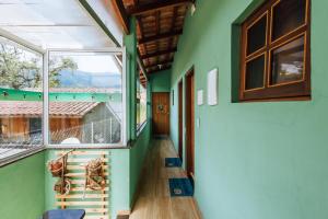 a hallway of a house with green walls and windows at pousada formibela in Ilhabela