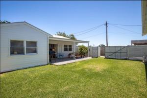 a backyard with a white house and a fence at Sorrento Beach Cottages No. 2 - in the heart of Sorrento in Sorrento