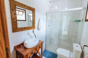 een badkamer met een toilet, een wastafel en een spiegel bij pousada formibela in Ilhabela