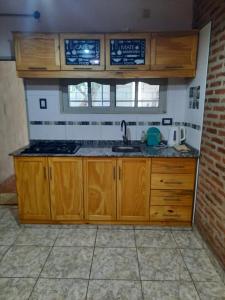 una cocina con armarios de madera y fregadero en Lo de Milo en Presidencia Roque Sáenz Peña