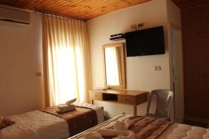 a bedroom with two beds and a television on the wall at Pilgrim's Guest House in Madaba