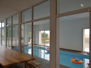 ein Haus mit einem Pool mit einem Tisch und Fenstern in der Unterkunft Gîte Brion, 5 pièces, 15 personnes - FR-1-591-188 in Brion
