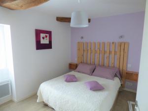 ein Schlafzimmer mit einem Bett mit lila Kissen darauf in der Unterkunft Gîte Le Bernard, 6 pièces, 10 personnes - FR-1-426-164 in Le Bernard