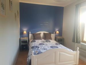 una camera con un letto bianco e una parete blu di Maison indépendante avec grand jardin, terrasse, plan d'eau sécurisé et salle de jeux près du lac d'Éguzon - FR-1-591-216 a Bazaiges