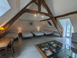 an attic room with three beds and a glass table at Gîte spacieux en pleine nature avec grand jardin, activités extérieures, proche sites historiques et commerces - FR-1-591-185 in Sarzay