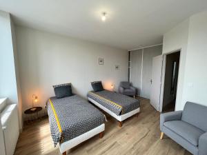 two beds in a room with a couch and a chair at École rénovée avec terrasse, 3 chambres, draps, ménage et chauffage inclus - FR-1-591-344 in Paudy