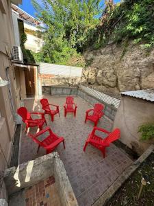 a group of red chairs and tables on a patio at Maison de ville proche marina in Le Marin