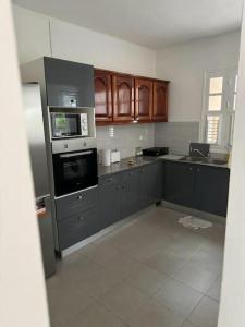 an empty kitchen with gray cabinets and appliances at Maison de ville proche marina in Le Marin