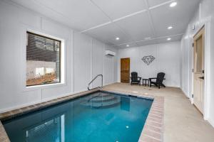 uma piscina numa sala de estar com mesa e cadeiras em SmokiesBoutiqueCabins would love to host you at our NEW cabin! 3 King Suites, Indoor Pool, Game Room, Lounge with 75" TV! Close to Dollywood and the Parkway! em Pigeon Forge