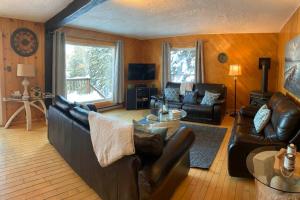 a living room with a leather couch and a table at Lake St-Joseph Waterfront SPA SAUNA Gaming room in Saint Adolphe D'Howard