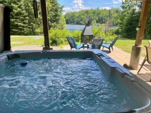 a large pool of water with chairs and a table at Lake St-Joseph Waterfront SPA SAUNA Gaming room in Saint Adolphe D'Howard
