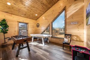 Habitación con mesa de ping pong en una cabaña de madera en SmokiesBoutiqueCabins would love to host you at our NEW cabin! 3 King Suites, Indoor Pool, Game Room, Lounge with 75" TV! Close to Dollywood and the Parkway! en Pigeon Forge