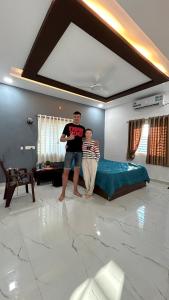 two people standing in a bedroom with a bed at Raj Homestay Hampi in Hampi