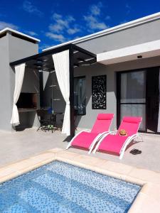 two pink chairs sitting next to a swimming pool at Tres Deseos in Villa Cura Brochero +56 photos