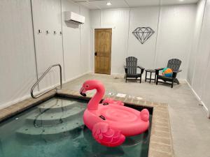 een zwembad met een roze zwaan in een kamer bij SmokiesBoutiqueCabins would love to host you at our NEW cabin! 3 King Suites, Indoor Pool, Game Room, Lounge with 75" TV! Close to Dollywood and the Parkway! in Pigeon Forge