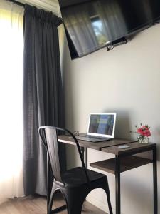 a desk with a laptop and a chair in a room at La casona Talpen in Constitución