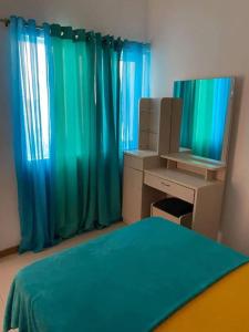 a bedroom with blue curtains and a desk and a mirror at Apartment in Achada São Filipe in Praia