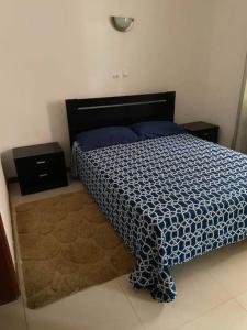 a bedroom with a bed with a blue and white comforter at Apartment in Achada São Filipe in Praia