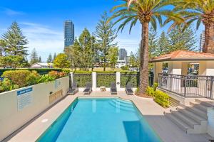 a swimming pool with palm trees and a building at Island Beach Resort in Gold Coast