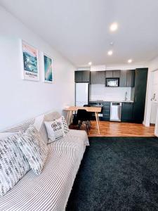 a living room with a couch and a kitchen with a table at Short Drive to Queenstown CBD - Cosy Guesthouse with Private Entrance and King Bed in Frankton