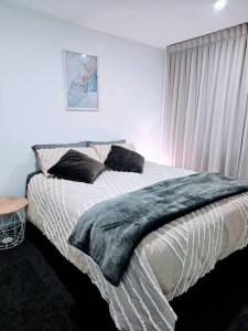 a bedroom with a bed with a blanket on it at Short Drive to Queenstown CBD - Cosy Guesthouse with Private Entrance and King Bed in Frankton