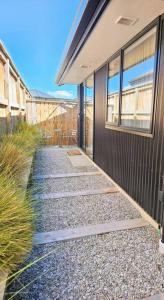 a walkway leading to the side of a building at Short Drive to Queenstown CBD - Cosy Guesthouse with Private Entrance and King Bed in Frankton