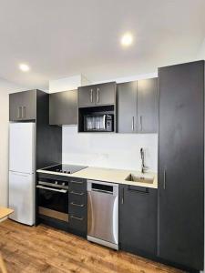 a kitchen with gray cabinets and a white refrigerator at Short Drive to Queenstown CBD - Cosy Guesthouse with Private Entrance and King Bed in Frankton