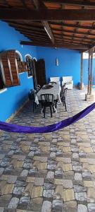 un patio con mesa, sillas y una pared azul en Casa OliMar fins de semana, en Bertioga